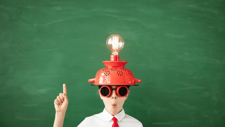 Child wearing a colander with a light bulb, pointing upwards with an idea