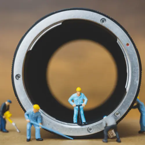 Miniature workers inspecting a large metal ring