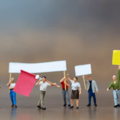 Miniature figure beside a speech bubble holding a puzzle piece
